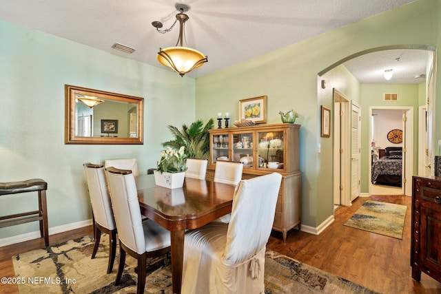 dining area featuring dark wood-type flooring and a textured ceiling