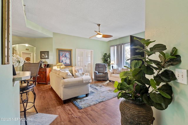 living room with ceiling fan, dark hardwood / wood-style floors, and a textured ceiling