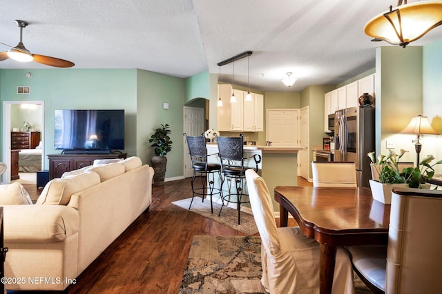 dining room with dark hardwood / wood-style flooring, ceiling fan, and a textured ceiling