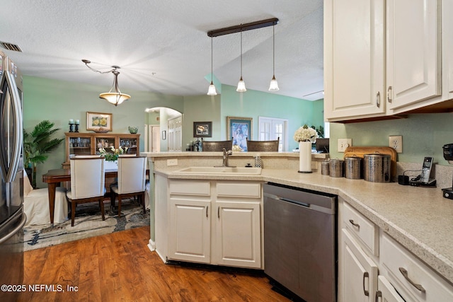 kitchen featuring appliances with stainless steel finishes, dark hardwood / wood-style floors, pendant lighting, sink, and white cabinets