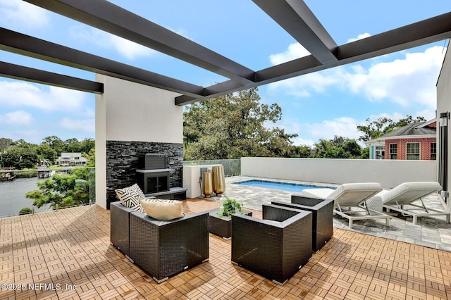 view of patio with a water view and an outdoor living space with a fireplace