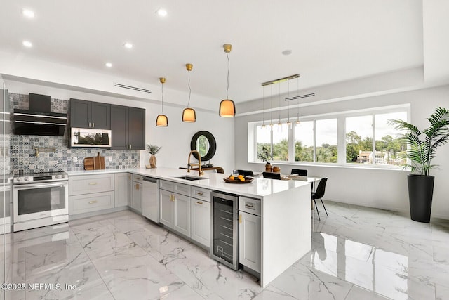 kitchen featuring pendant lighting, sink, wine cooler, stainless steel appliances, and wall chimney exhaust hood