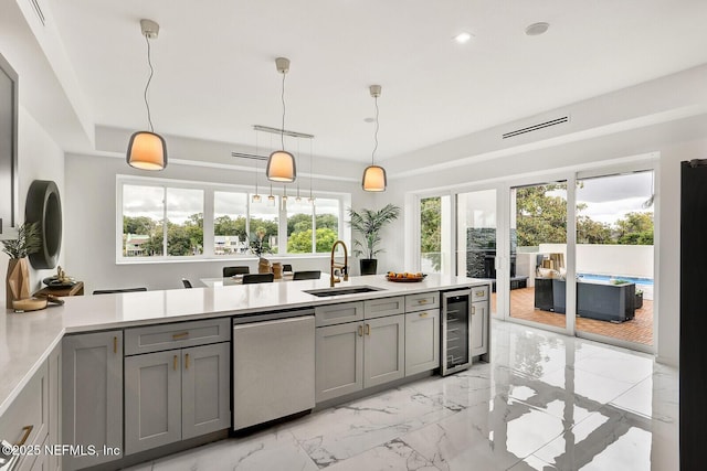 kitchen with pendant lighting, sink, gray cabinets, stainless steel dishwasher, and beverage cooler