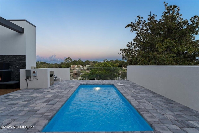 pool at dusk with a patio area