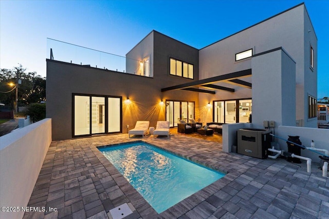 back house at dusk with an outdoor living space, a fenced in pool, and a patio area