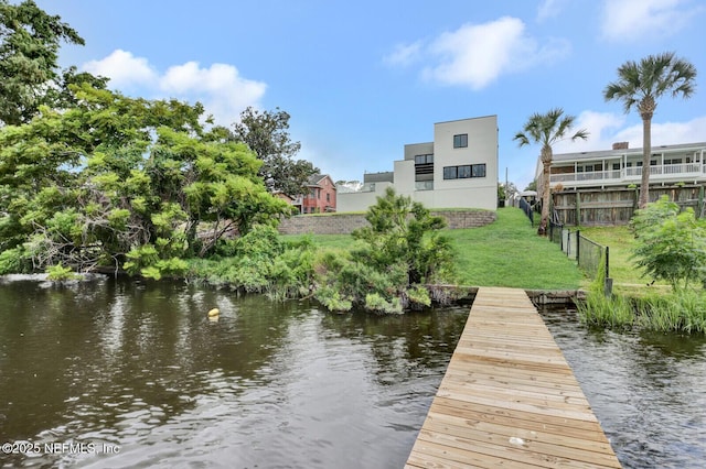 view of dock with a yard and a water view