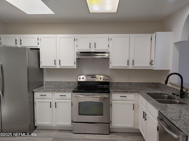 kitchen with appliances with stainless steel finishes, a sink, white cabinetry, and under cabinet range hood