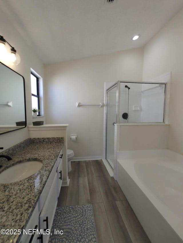 full bathroom with toilet, vanity, a garden tub, wood finish floors, and a shower stall