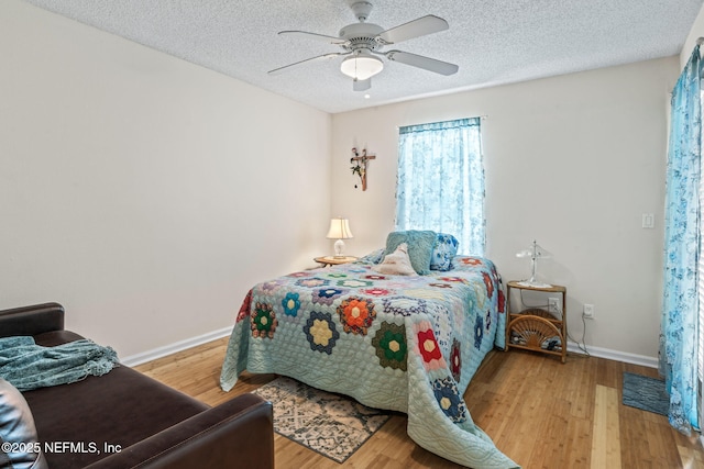 bedroom featuring hardwood / wood-style flooring, ceiling fan, and a textured ceiling