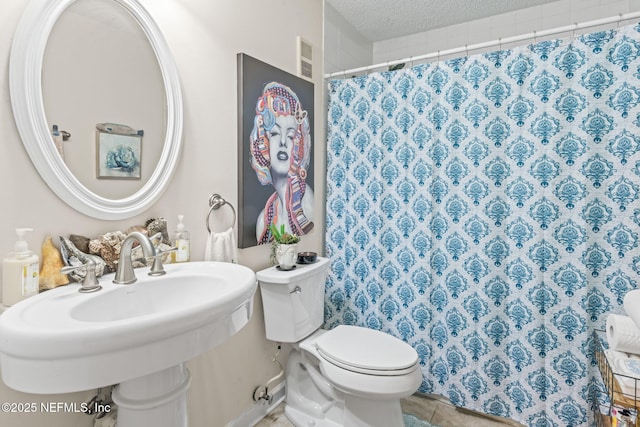 bathroom featuring tile patterned flooring, sink, toilet, and a textured ceiling