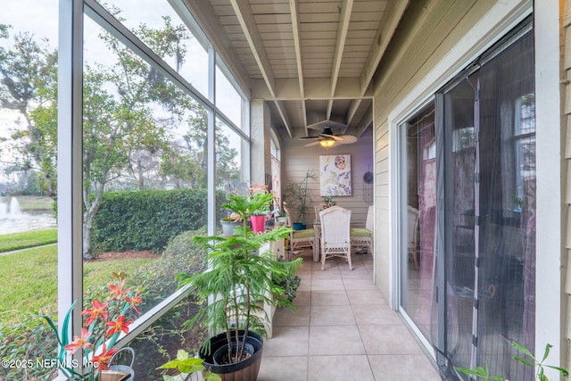 unfurnished sunroom with ceiling fan and beam ceiling