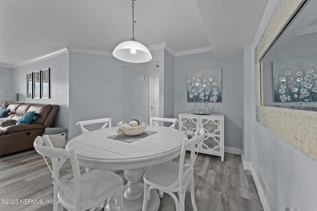 dining room with ornamental molding, a textured ceiling, baseboards, and wood finished floors