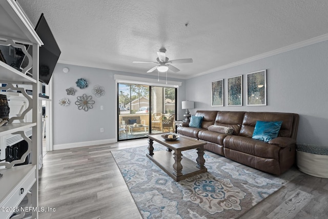 living area with baseboards, a ceiling fan, ornamental molding, wood finished floors, and a textured ceiling