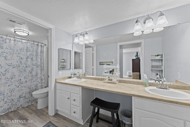 full bathroom with double vanity, visible vents, a sink, and wood finished floors