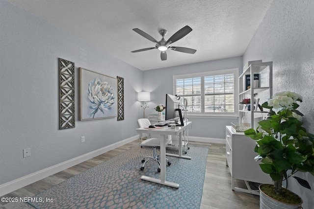 home office featuring a ceiling fan, a textured ceiling, baseboards, and wood finished floors