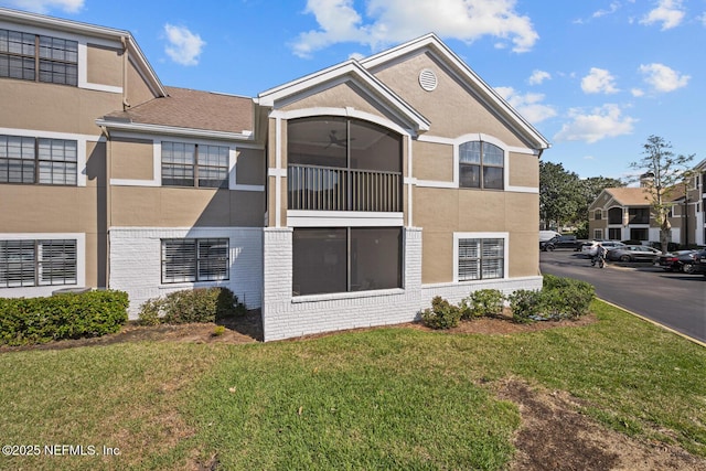 back of property with brick siding, a lawn, and stucco siding