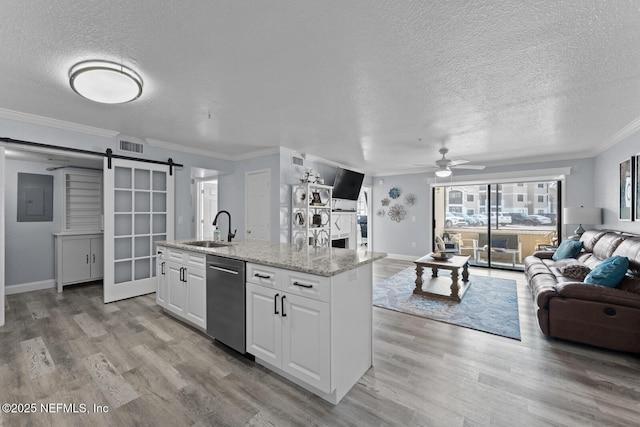 kitchen with a barn door, open floor plan, a sink, light wood-type flooring, and dishwasher