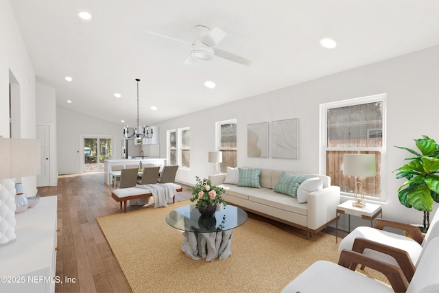 living area featuring lofted ceiling, ceiling fan with notable chandelier, wood-type flooring, and recessed lighting