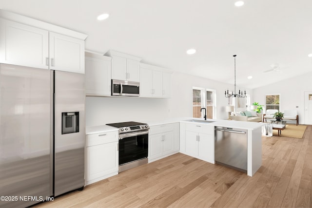 kitchen featuring a sink, open floor plan, light countertops, appliances with stainless steel finishes, and an inviting chandelier