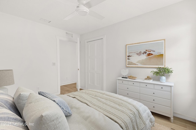 bedroom featuring light wood-type flooring, a closet, baseboards, and a ceiling fan