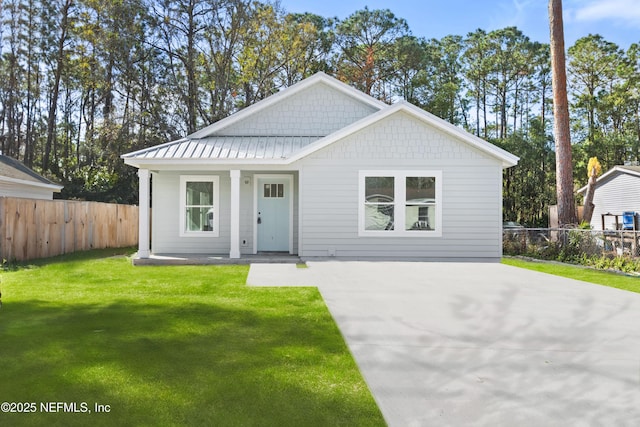 view of front of house featuring a standing seam roof, metal roof, fence, and a front lawn