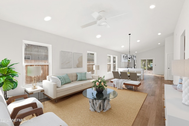 living room featuring lofted ceiling, light wood-style floors, ceiling fan with notable chandelier, and recessed lighting