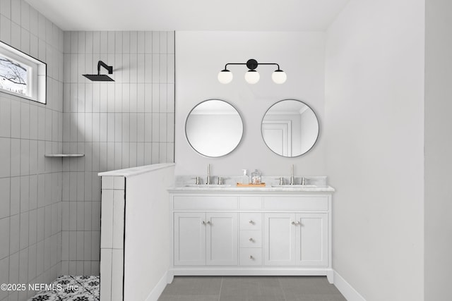 bathroom with a walk in shower, double vanity, a sink, and baseboards