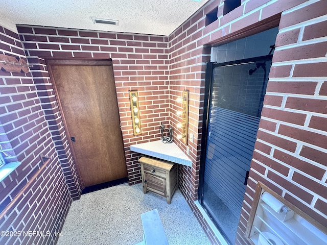 bathroom with brick wall and a textured ceiling