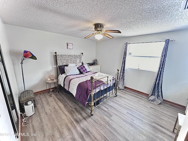 bedroom with hardwood / wood-style flooring, ceiling fan, and a textured ceiling