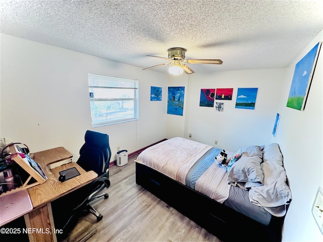 bedroom with ceiling fan, a textured ceiling, and light hardwood / wood-style flooring