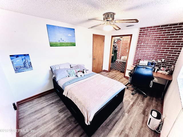 bedroom featuring hardwood / wood-style floors, brick wall, a textured ceiling, and ceiling fan