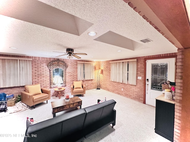 living room with brick wall, light carpet, a textured ceiling, and ceiling fan