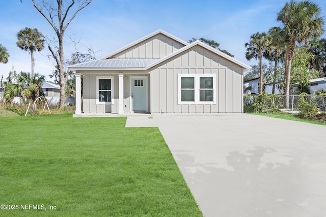 modern farmhouse style home with metal roof, fence, a front lawn, and board and batten siding