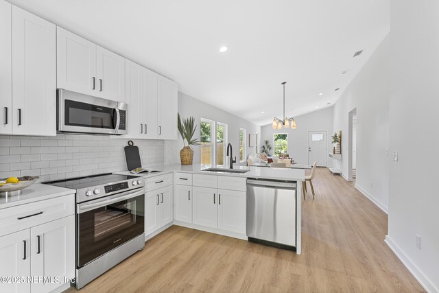 420 Herbert St, Saint Augustine, FL 32084 - kitchen featuring a peninsula, light wood-style flooring, stainless steel appliances, and a sink