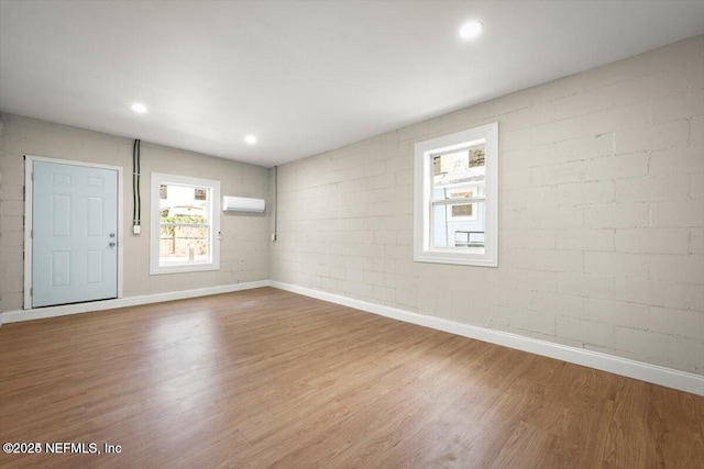 unfurnished room featuring hardwood / wood-style flooring and a wall unit AC