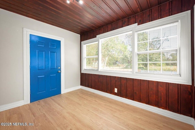 foyer entrance featuring a healthy amount of sunlight, wooden ceiling, wooden walls, and light hardwood / wood-style flooring