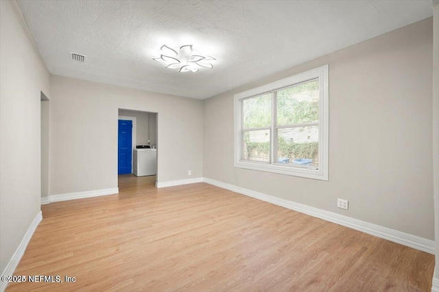 unfurnished room featuring washer / clothes dryer, a textured ceiling, and light hardwood / wood-style floors