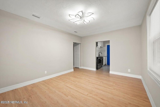 unfurnished bedroom featuring sink, light hardwood / wood-style flooring, and a textured ceiling