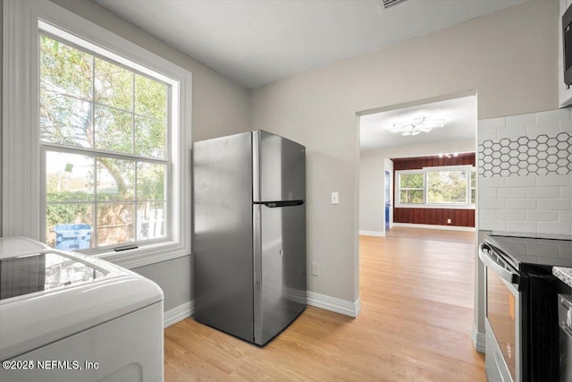 kitchen with washer / clothes dryer, decorative backsplash, light hardwood / wood-style flooring, and appliances with stainless steel finishes