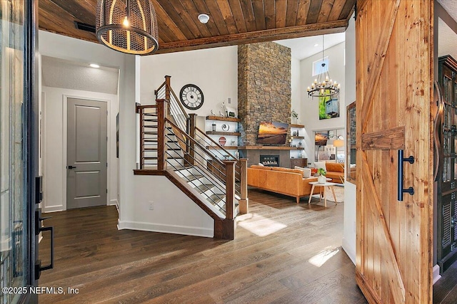 entrance foyer with an inviting chandelier, a fireplace, dark hardwood / wood-style flooring, and wooden ceiling