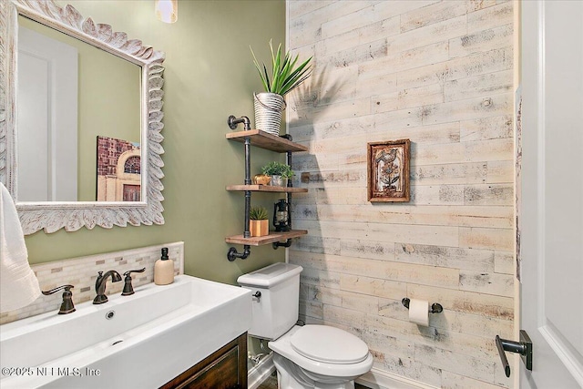 bathroom with vanity, wooden walls, and toilet