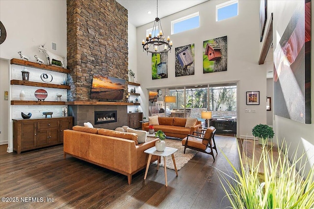 living room with an inviting chandelier, a fireplace, dark wood-type flooring, and a high ceiling