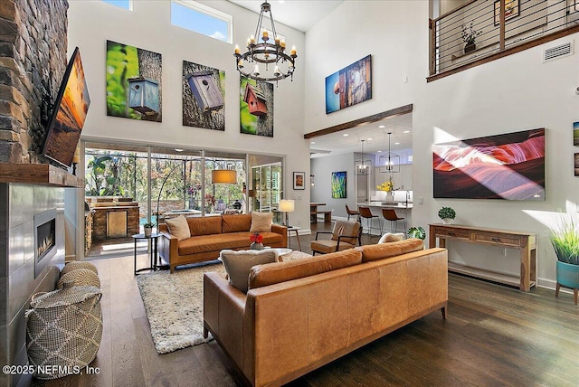 living room with a tiled fireplace, plenty of natural light, dark hardwood / wood-style floors, and a chandelier