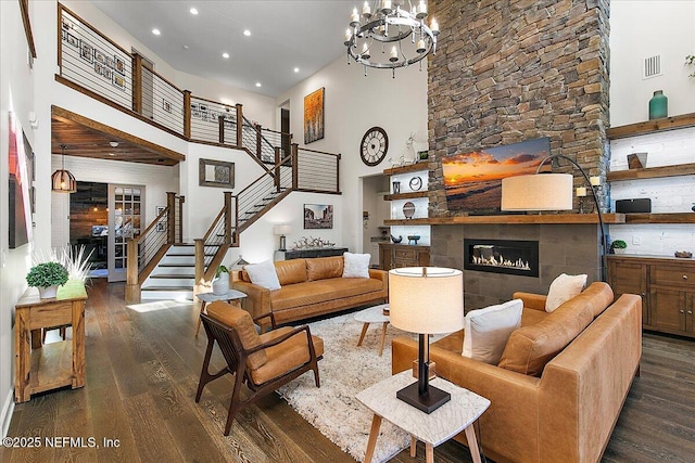 living room with dark hardwood / wood-style floors, a fireplace, an inviting chandelier, and a high ceiling