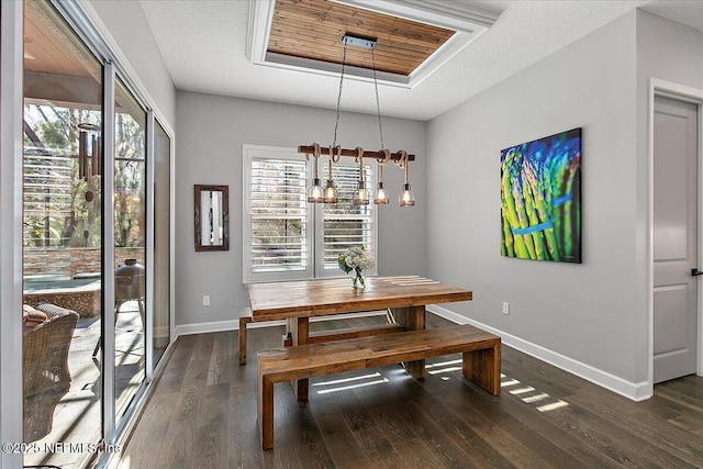 dining space with dark hardwood / wood-style floors, a textured ceiling, and a tray ceiling