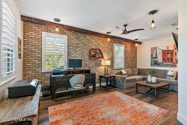 living room featuring dark hardwood / wood-style flooring, a textured ceiling, and brick wall