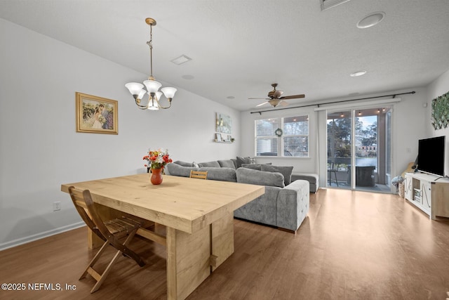 dining room with ceiling fan with notable chandelier, wood finished floors, visible vents, and baseboards