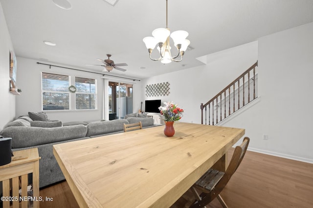 dining room with dark wood-style flooring, stairway, baseboards, and ceiling fan with notable chandelier