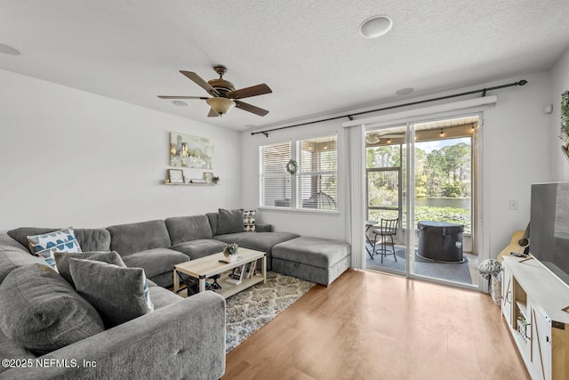 living area featuring light wood-style flooring, a ceiling fan, and a textured ceiling