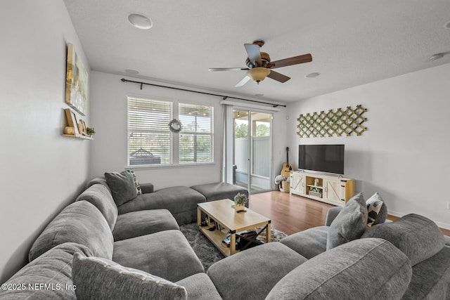 living area with baseboards, a ceiling fan, and wood finished floors